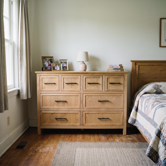 Cozy bedroom featuring a light wood dresser, minimalist decor, and a quilt-covered bed in a warm, traditional home setting.